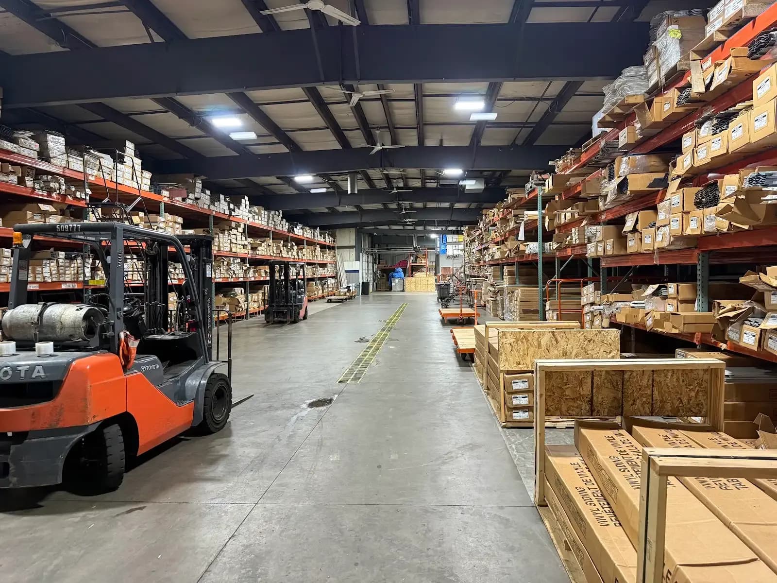 Siding warehouse aisle with a forklift and racked cartons